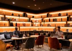 a man sits at a table using a laptop in a library