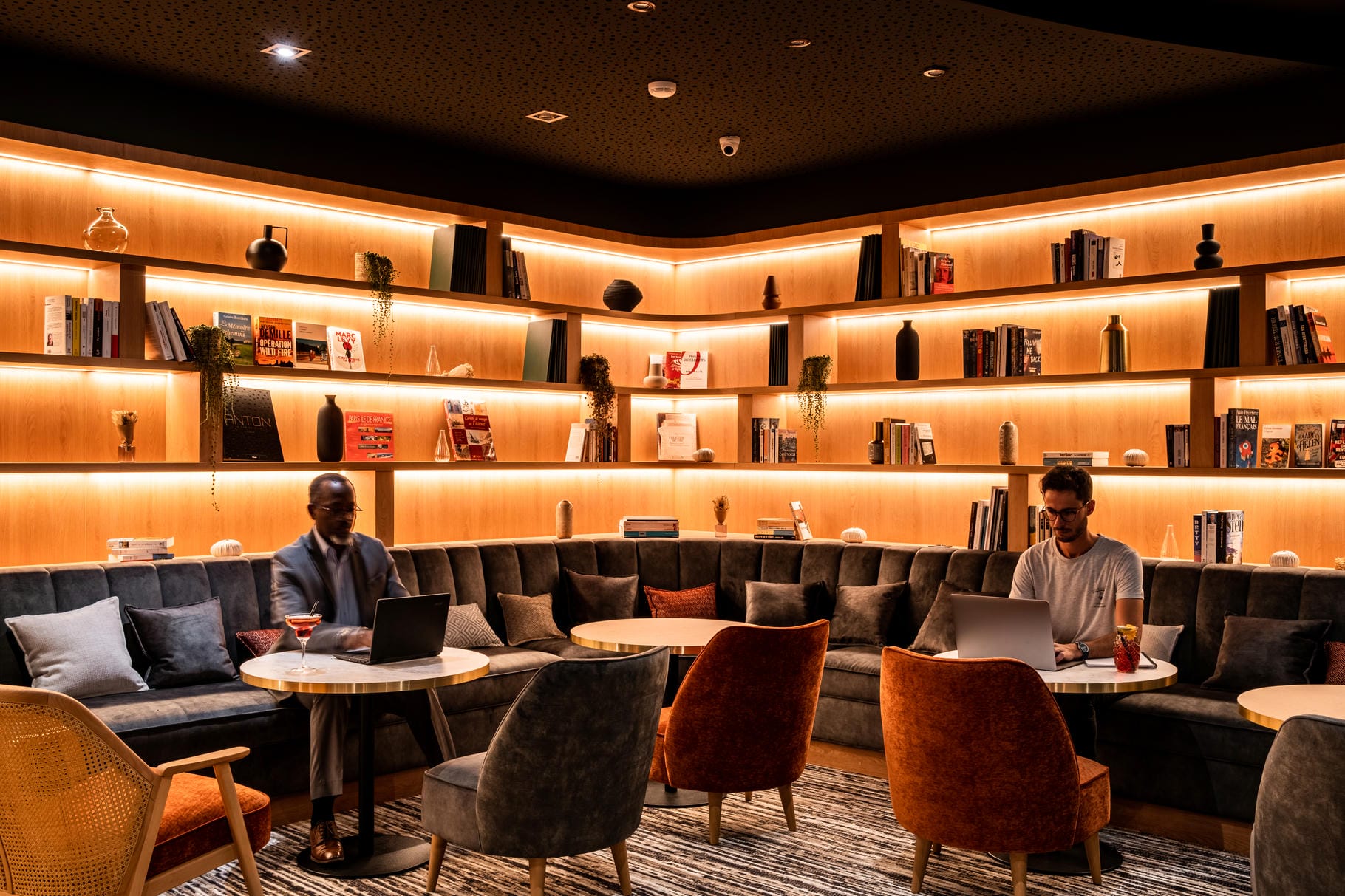 un homme assis à une table utilisant un ordinateur portable dans une bibliothèque