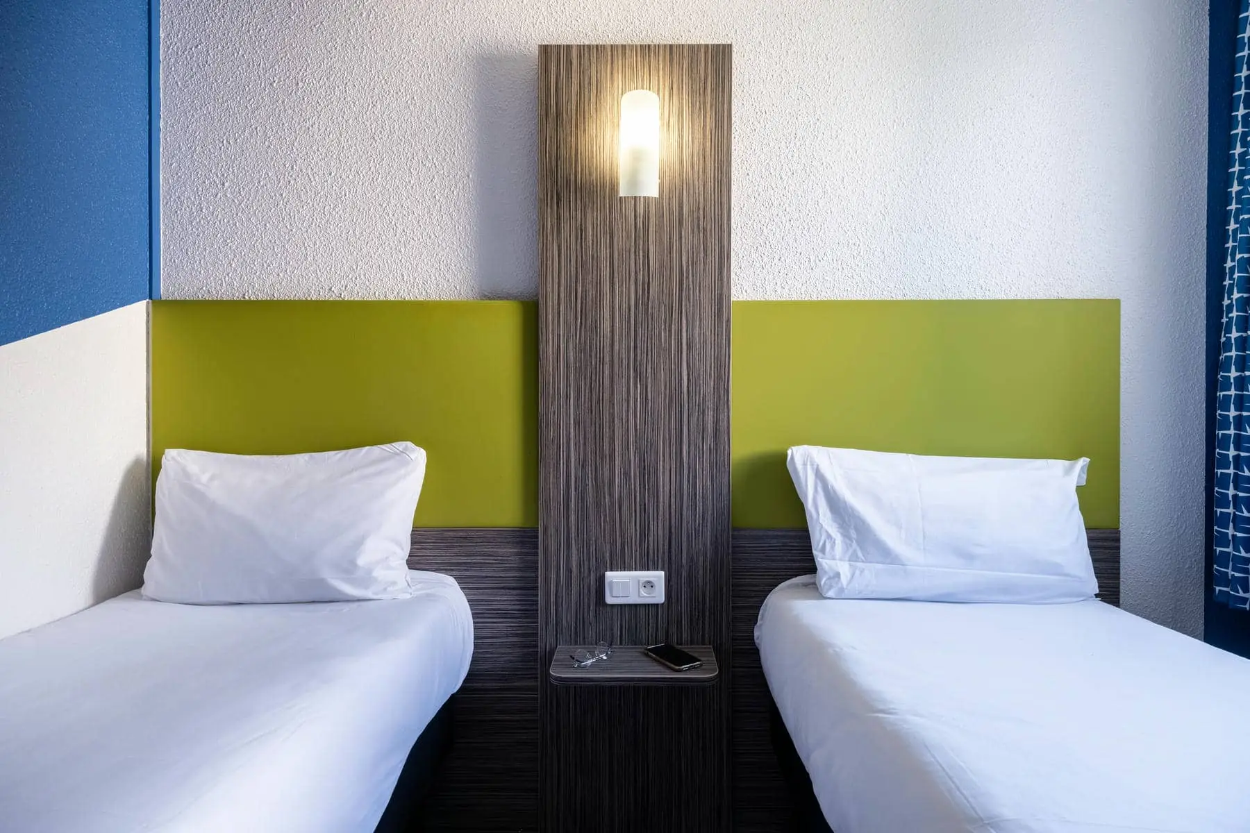 une chambre d'hôtel avec deux lits et une lumière sur le mur