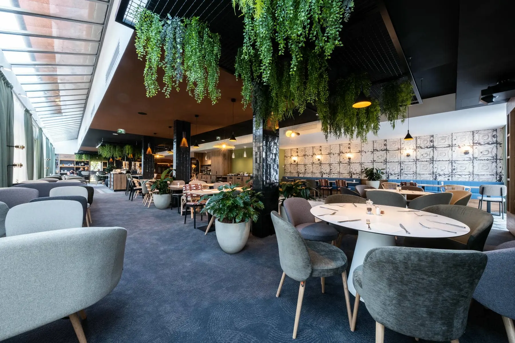 un restaurant avec des tables et des chaises et des plantes suspendues au plafond