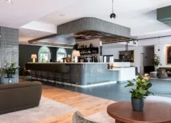 en::hotel lobby and reception with a central tiled bar, artistic ceiling painting, lounge seating, and access to the garden terrace fr::lobby de l’hôtel avec réception autour d’un bar central carrelé, peinture artistique au plafond, assises lounge et accès à la terrasse sur jardin