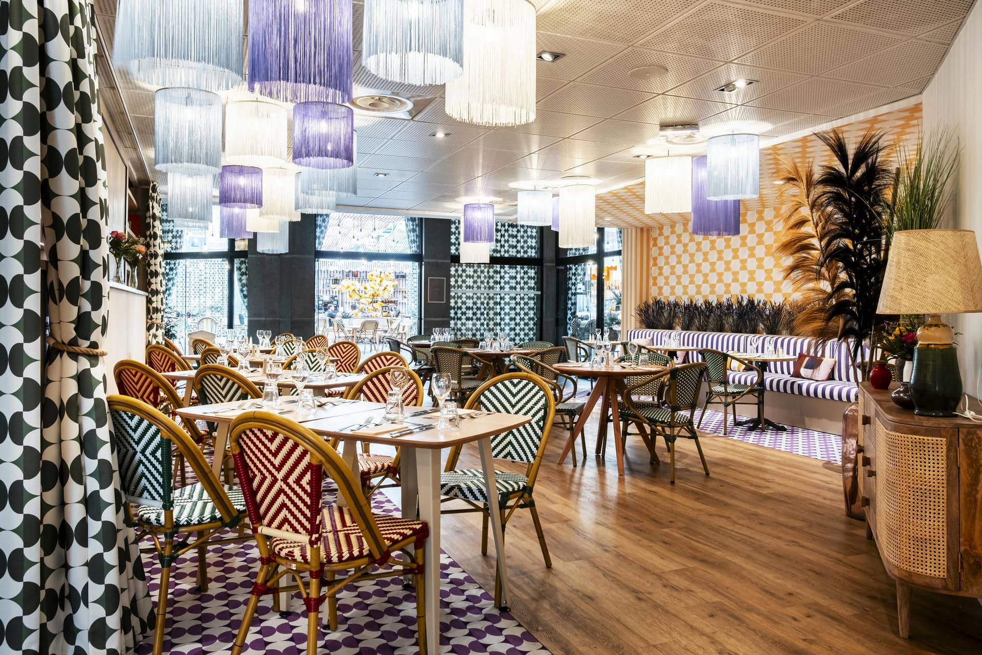 tables et chaises dans un restaurant avec des lampes violettes et blanches suspendues au plafond