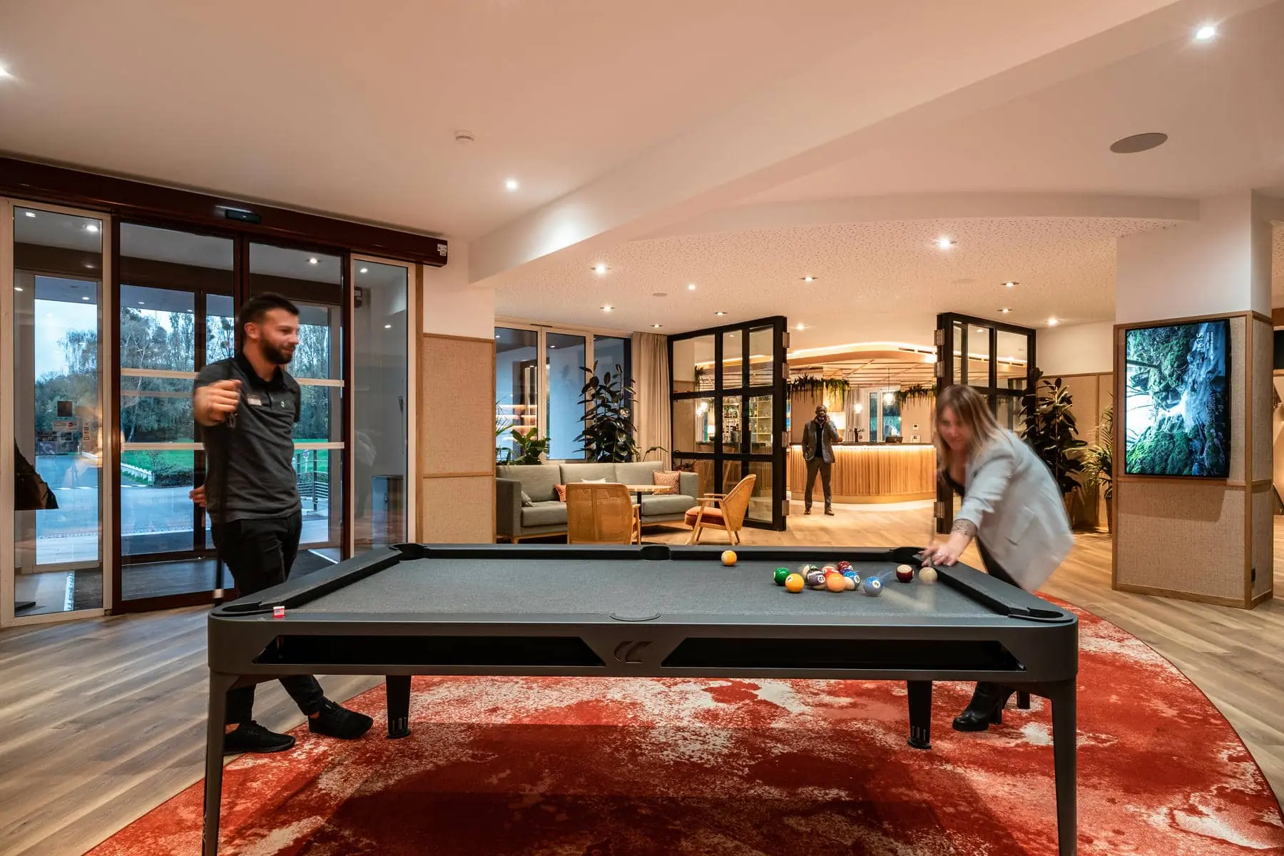 un homme et une femme jouent au billard dans un hall d'entrée