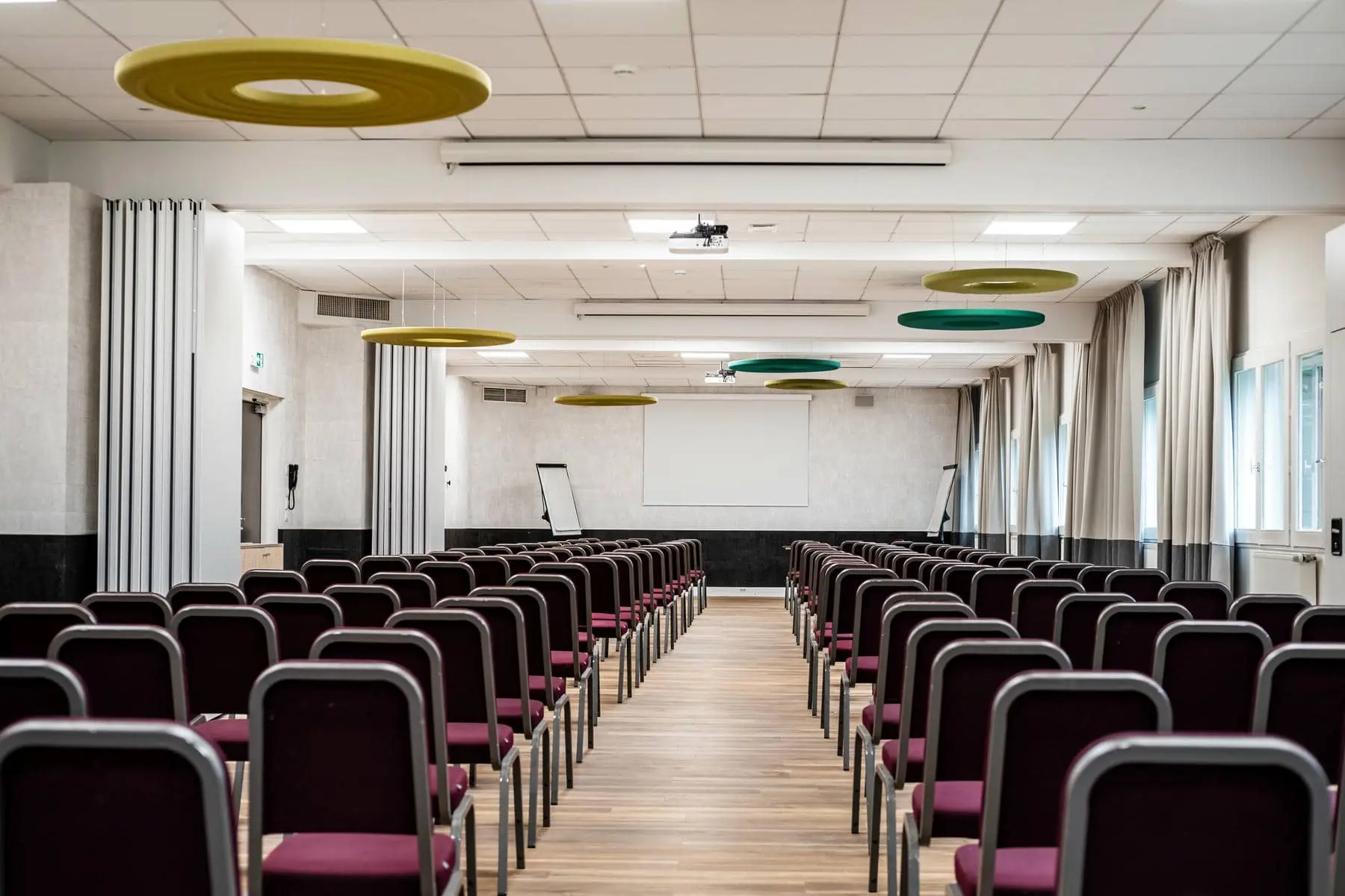 des rangées de chaises dans une grande salle avec un écran de projection