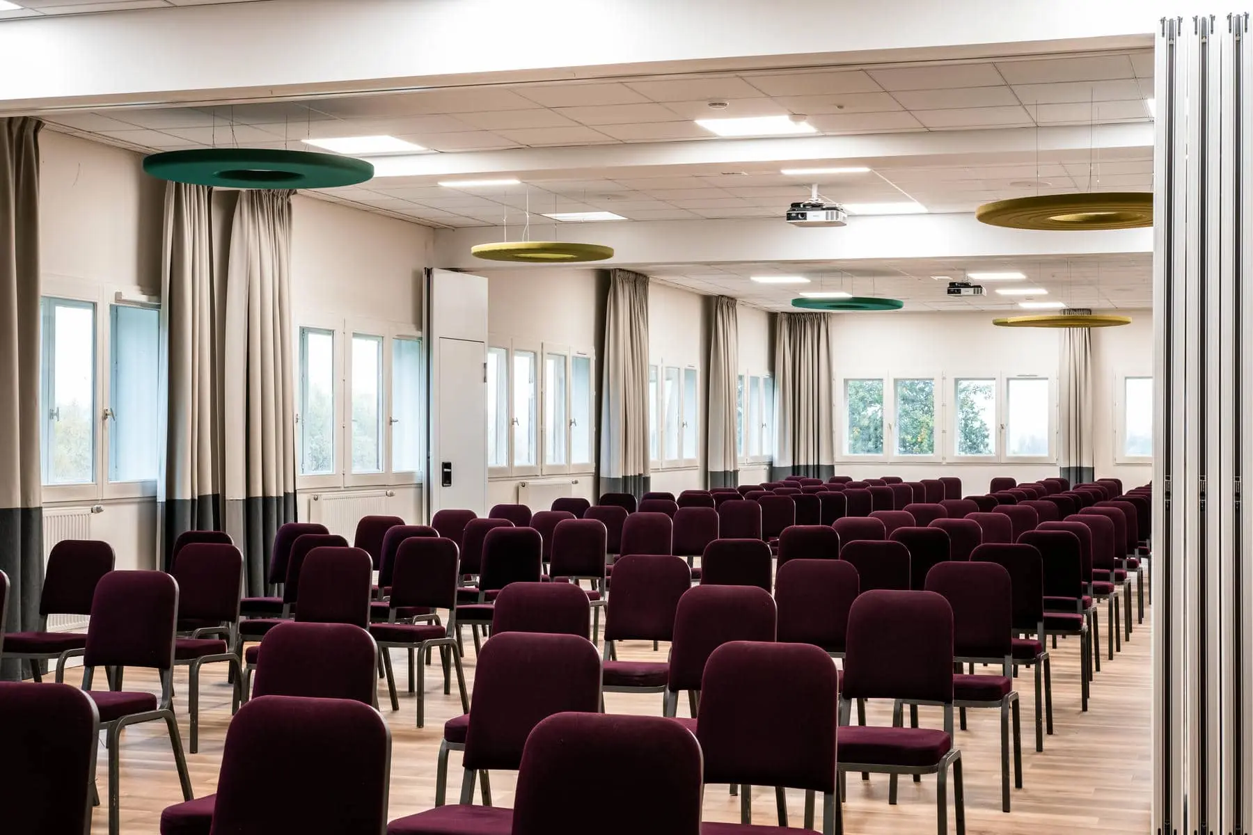 une grande salle avec des rangées de chaises et un projecteur au plafond