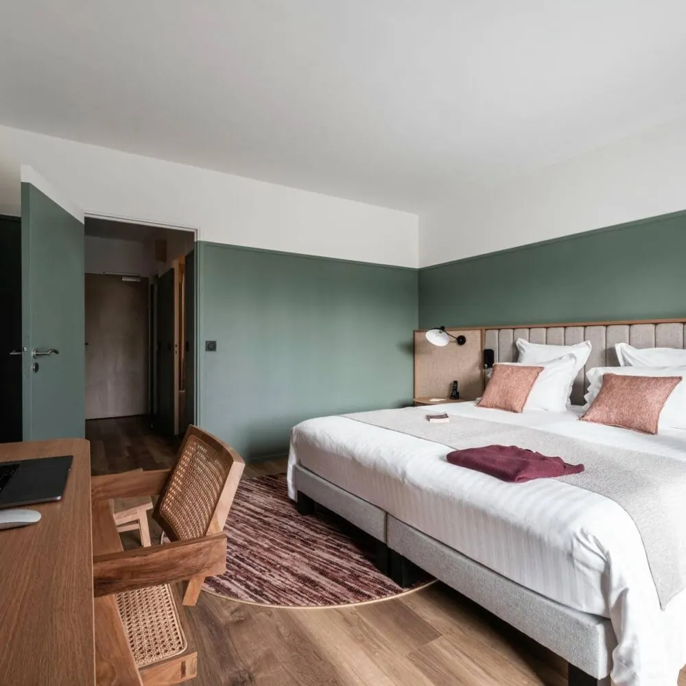 une chambre d'hôtel avec un grand lit et un bureau sur lequel est posé un ordinateur portable