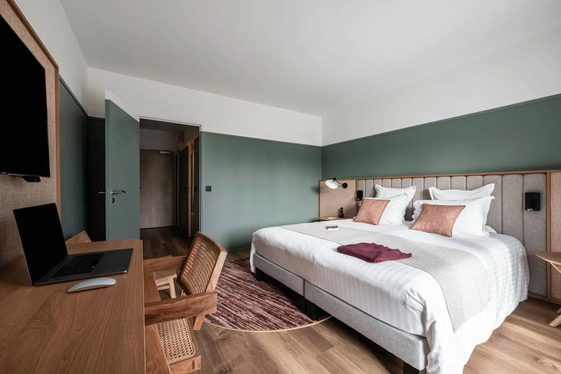 une chambre d'hôtel avec un grand lit et un bureau sur lequel est posé un ordinateur portable