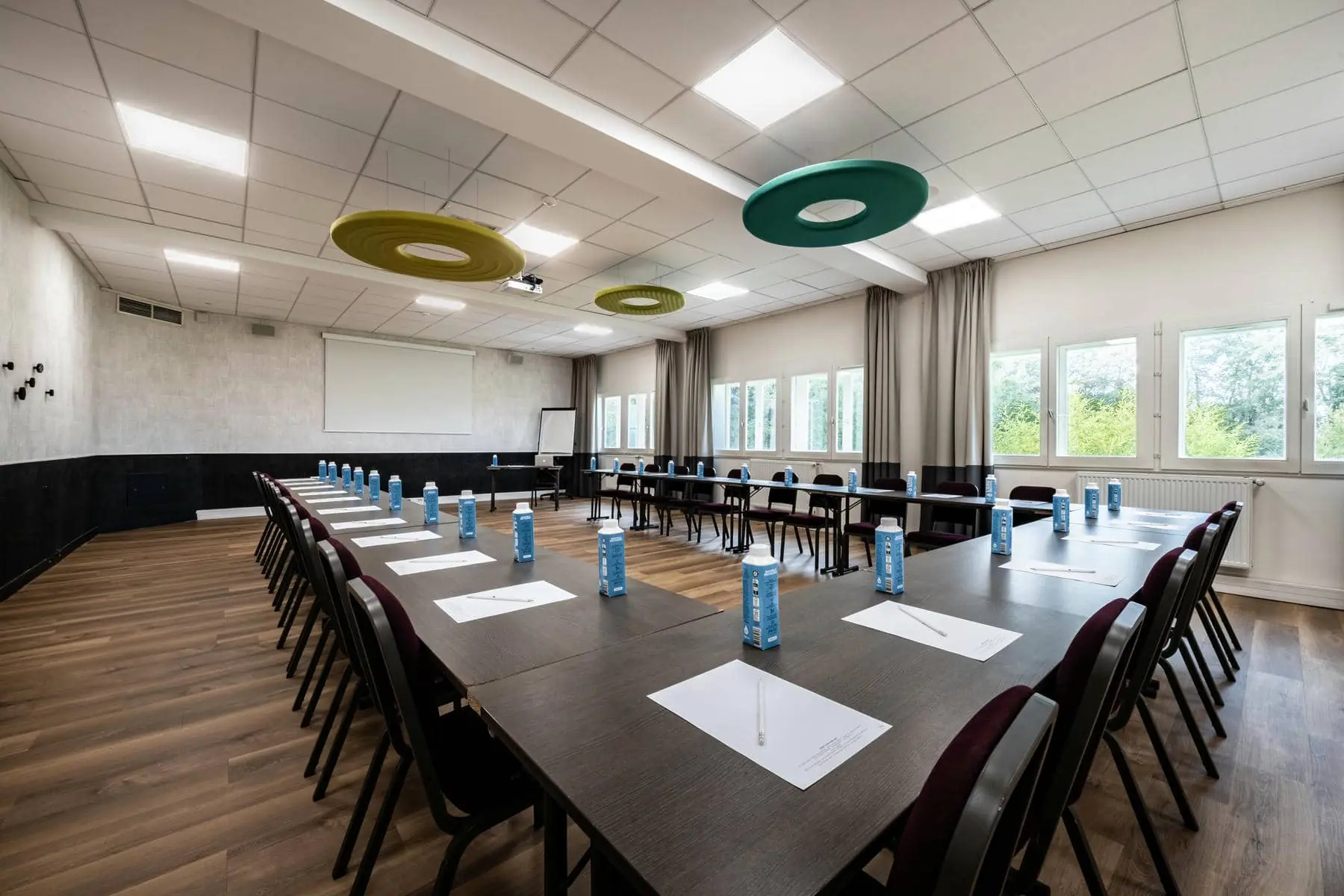 une salle de conférence avec des tables et des chaises et un écran de projection