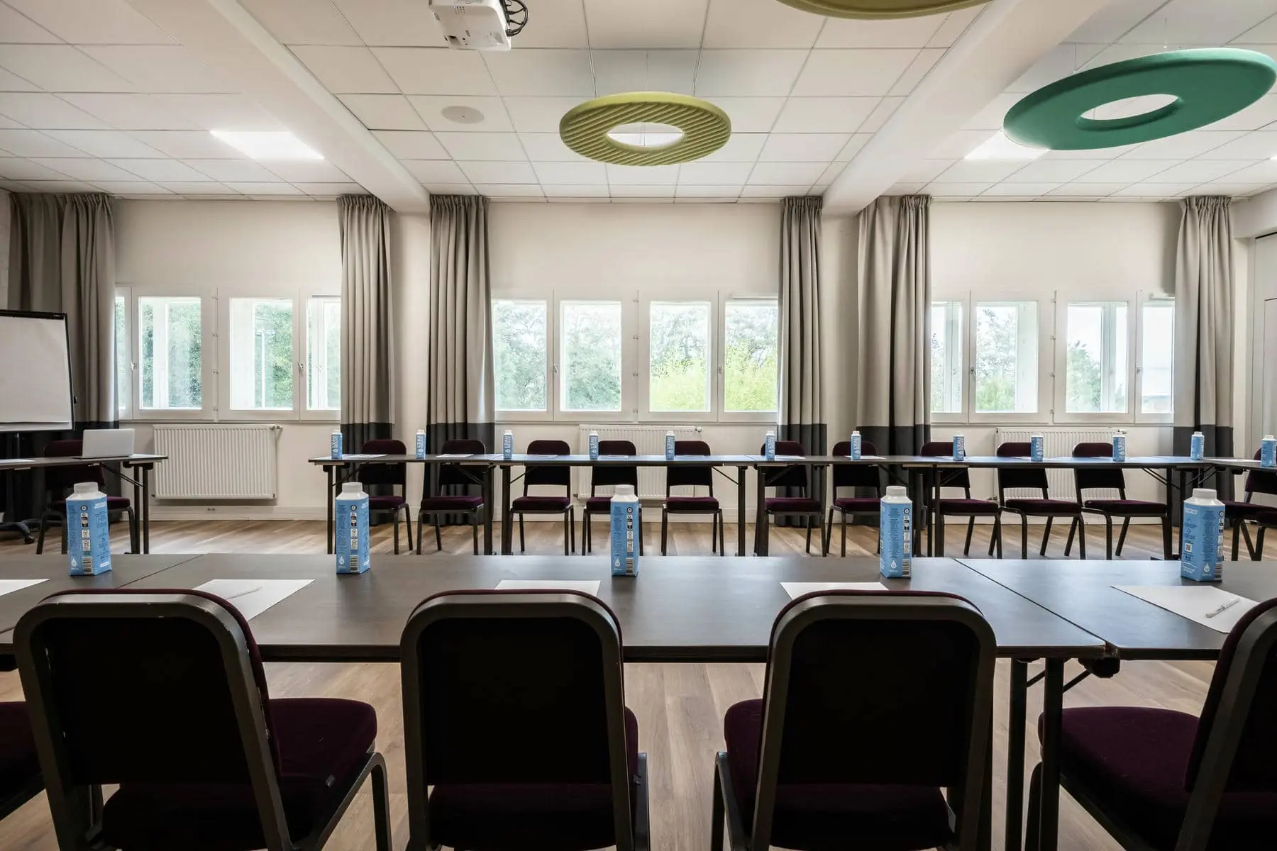 une salle de conférence avec tables et chaises et un projecteur