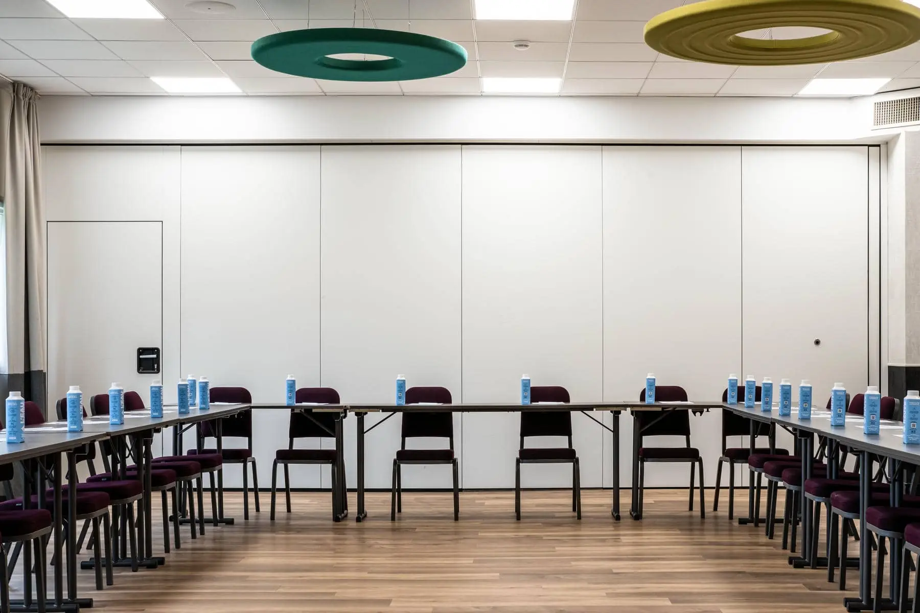 une salle de conférence avec des tables et des chaises sur lesquelles sont posées des bouteilles d'eau