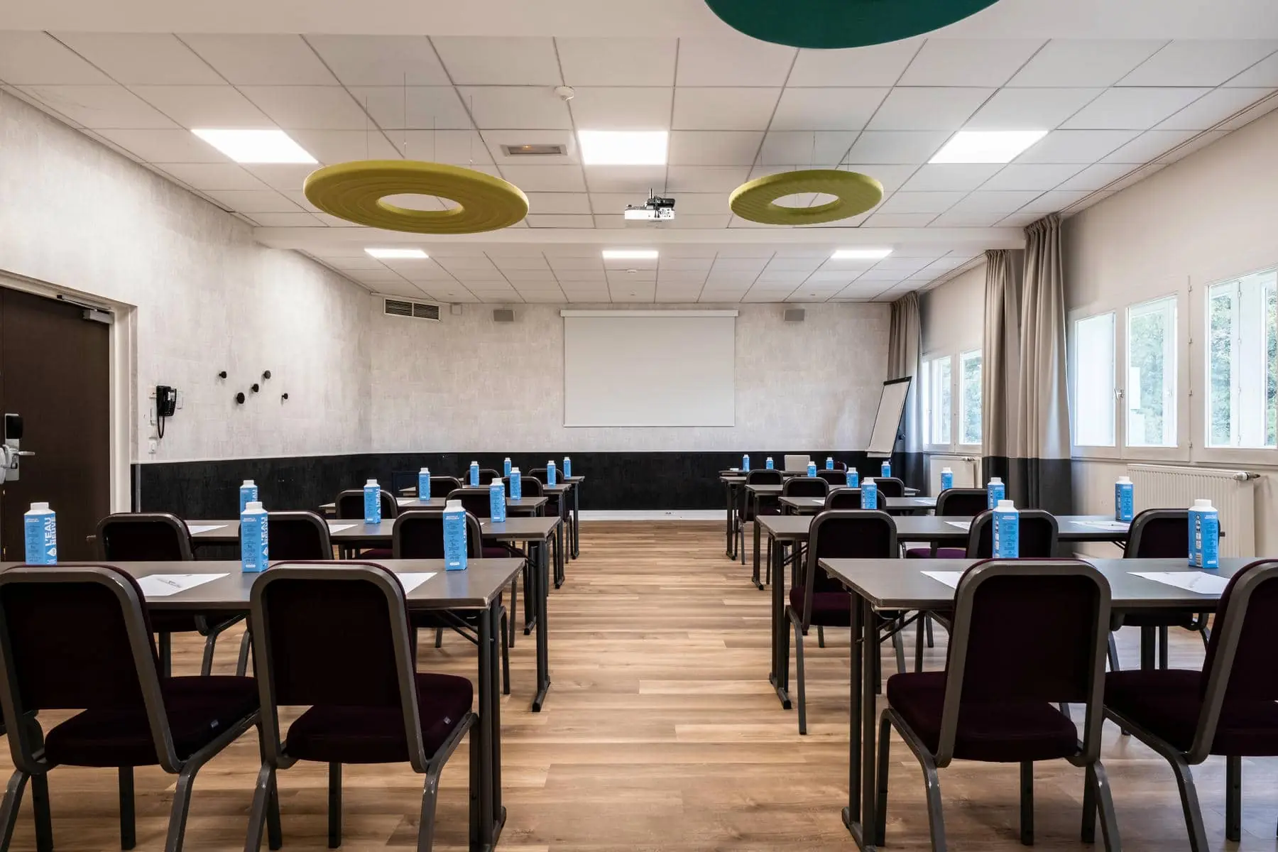 des rangées de tables et de chaises sur lesquelles sont posées des bouteilles d'eau bleues