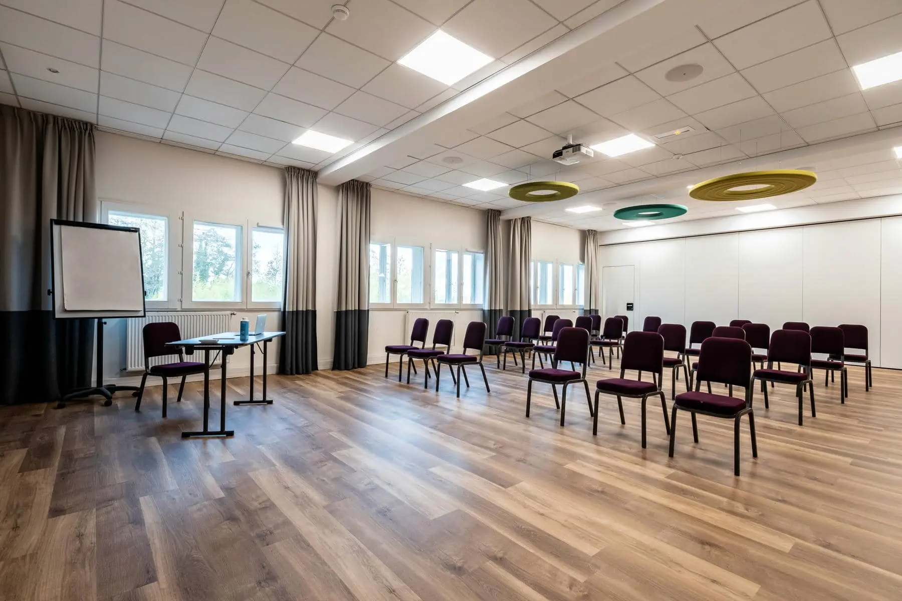 une salle de conférence avec des tables et des chaises et un projecteur au plafond