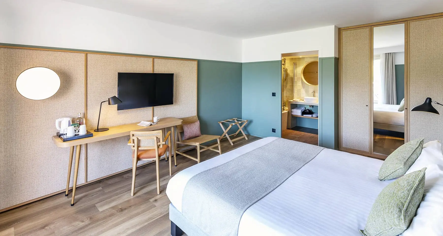 une chambre d'hôtel avec un grand lit, un bureau et une télévision à écran plat