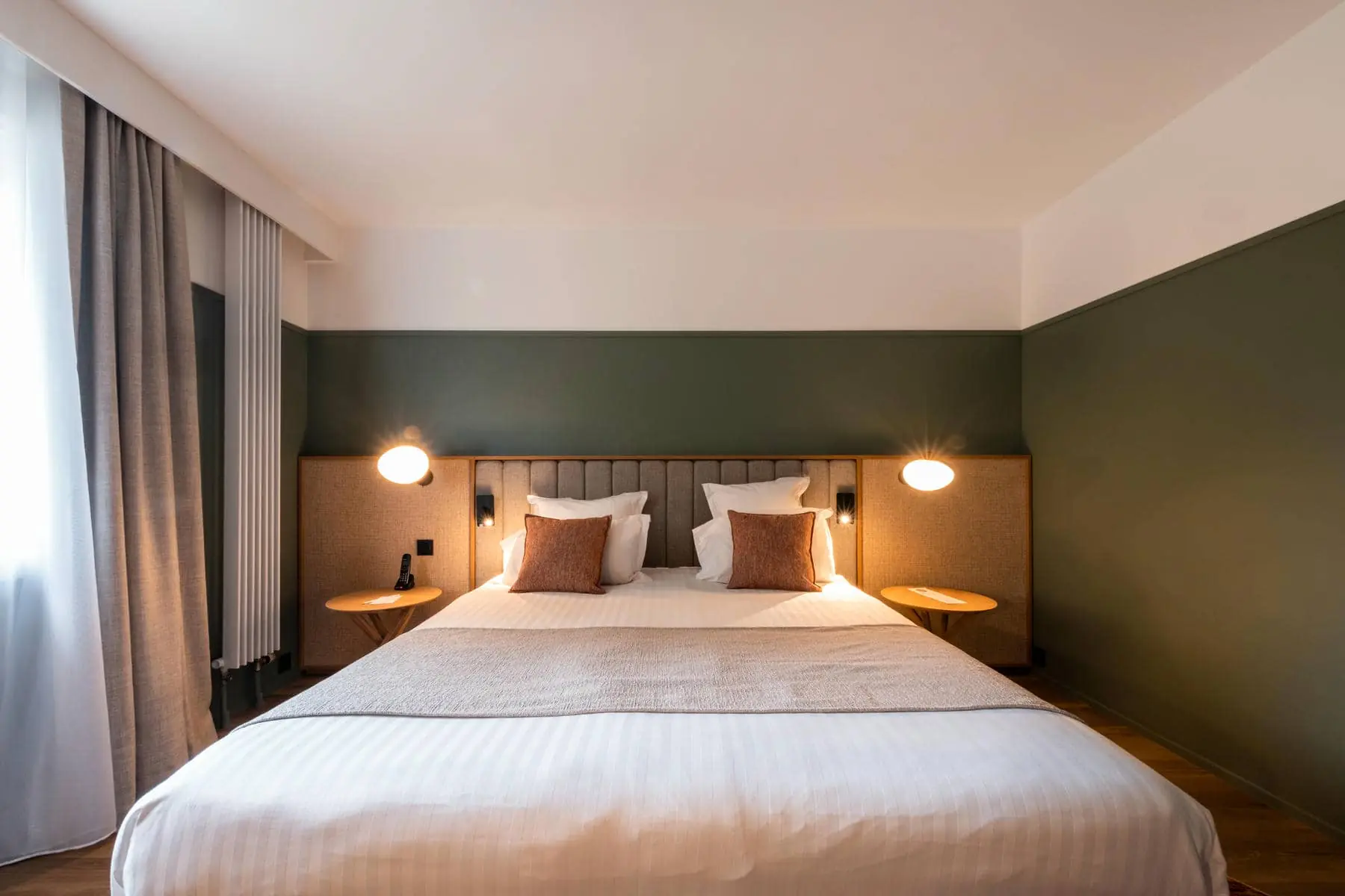 une chambre d'hôtel avec un lit et deux lampes au mur