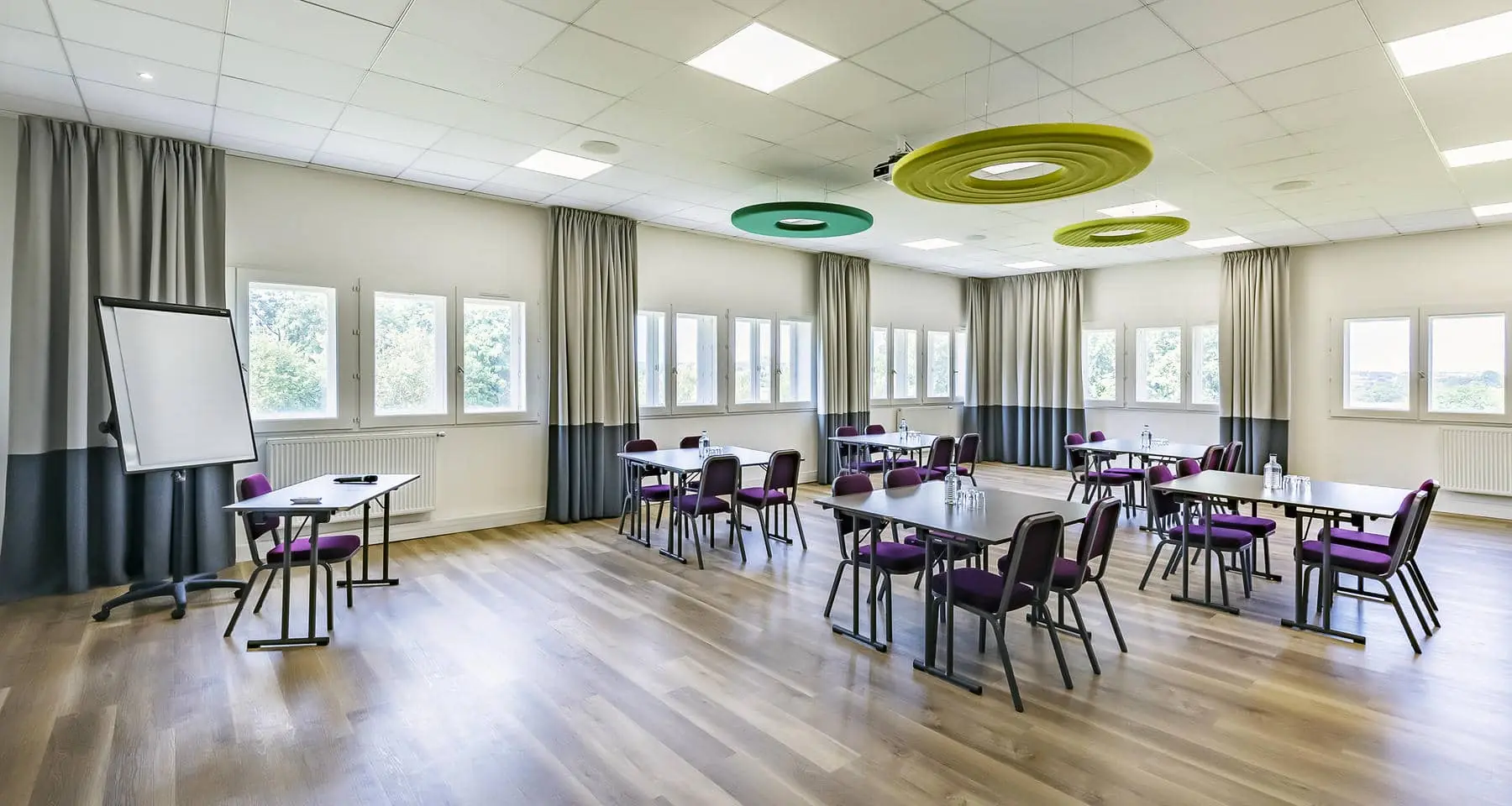 une salle de conférence avec des tables et des chaises et un tableau blanc
