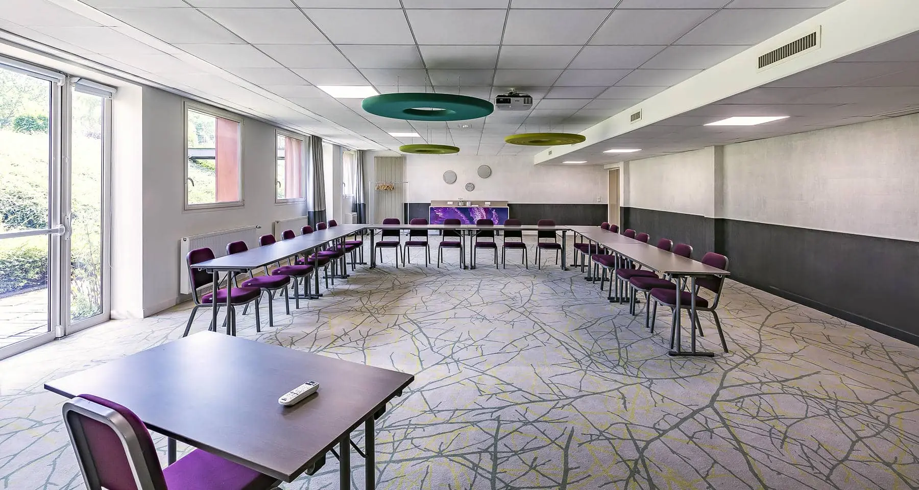 une salle avec des tables et des chaises et un projecteur au plafond