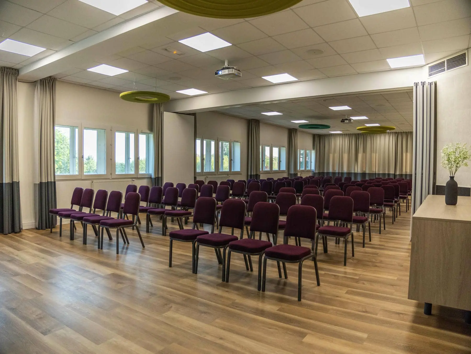une grande salle avec des rangées de chaises et un projecteur au plafond