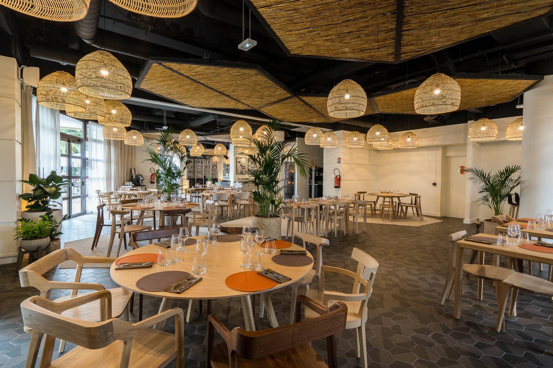 un restaurant avec des tables et des chaises et des lampes en osier suspendues au plafond