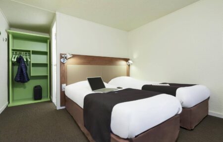 a hotel room with two beds and a laptop on the bed