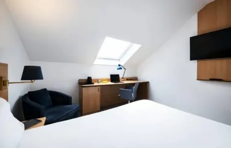 une chambre d'hôtel avec un bureau, une chaise et une télévision à écran plat