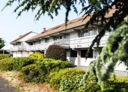 un bâtiment blanc avec un balcon et quelques arbres devant lui