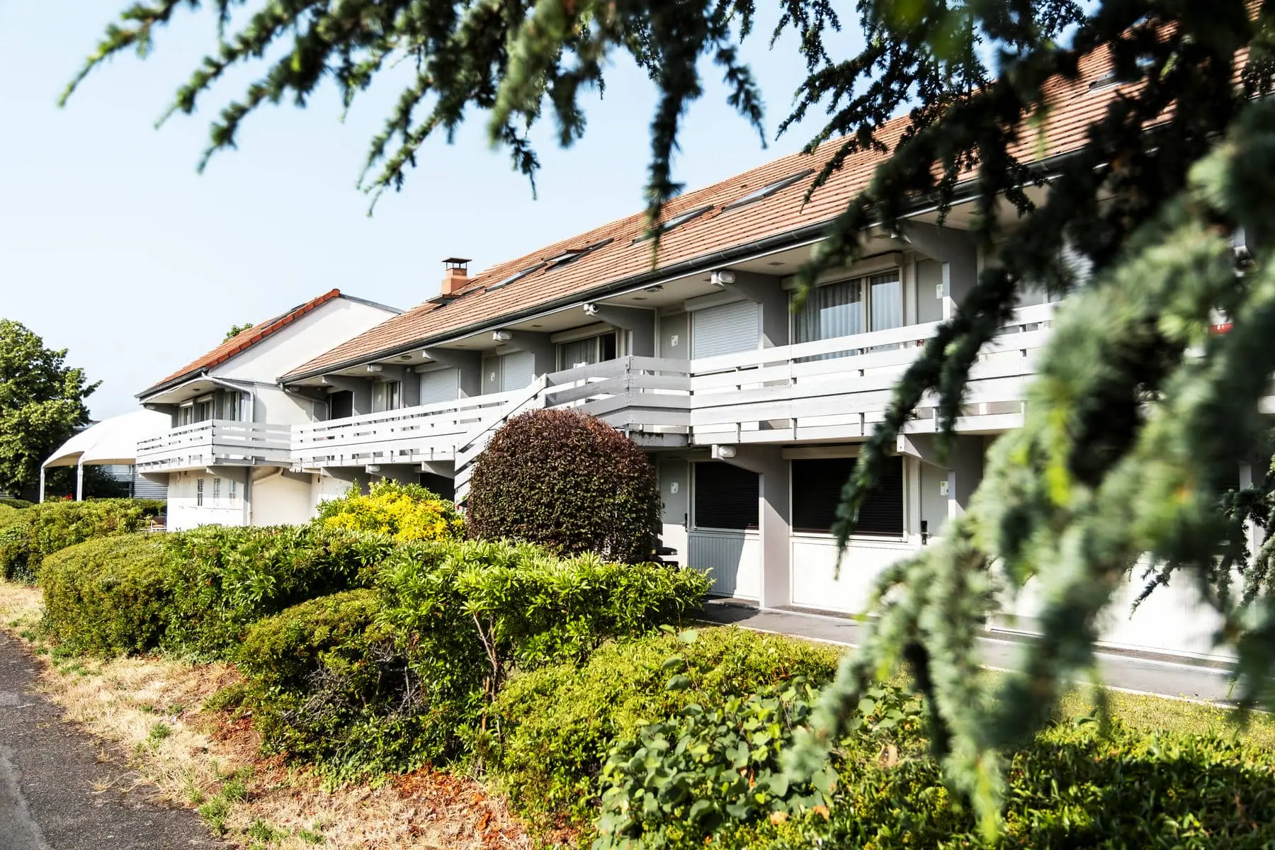 un bâtiment blanc avec un balcon et quelques arbres devant lui
