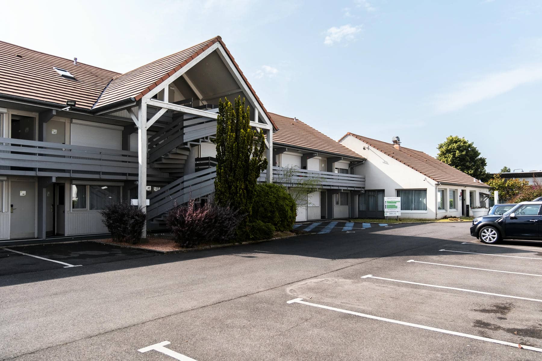 un parking devant un bâtiment avec un panneau indiquant " hôtel "