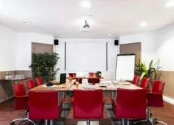 une salle de conférence avec des chaises rouges et un écran de projection