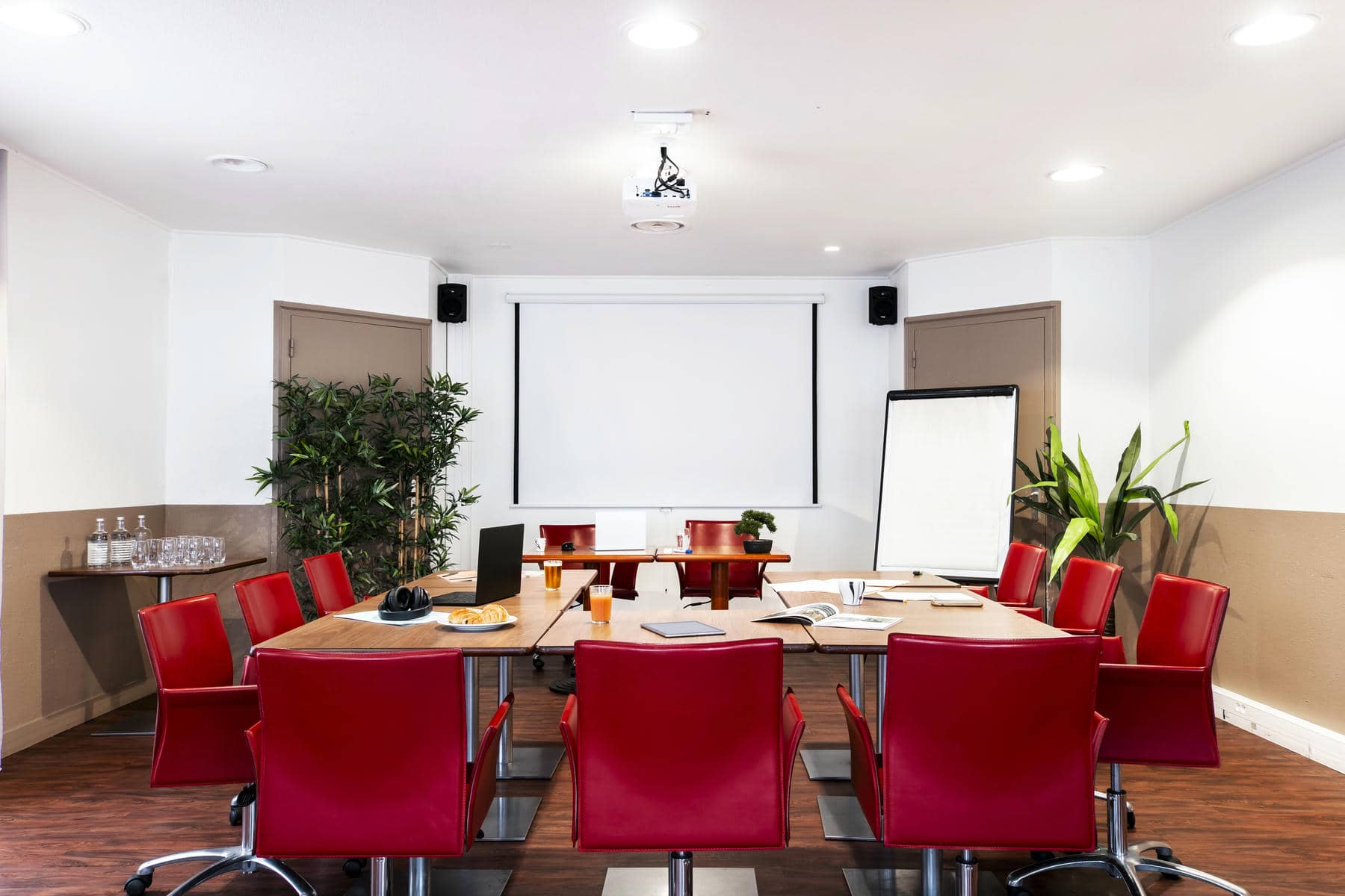une salle de conférence avec des chaises rouges et un écran de projection