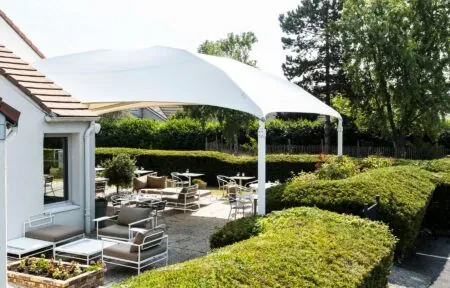 un patio avec des tables et des chaises sous un auvent blanc