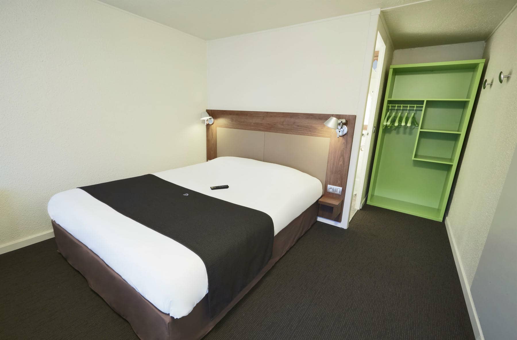 a hotel room with a single bed and a green closet