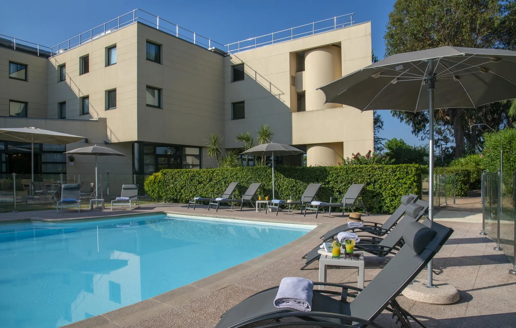 une piscine avec des chaises et des parasols devant un bâtiment