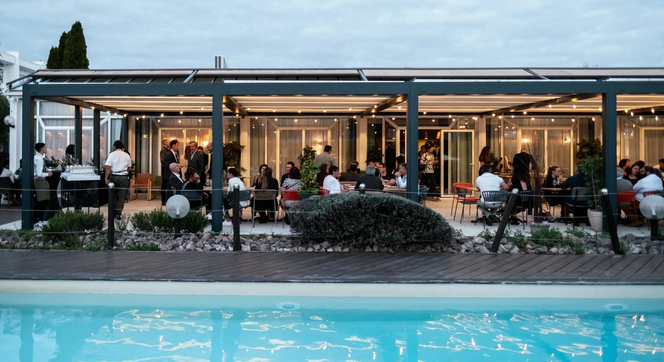 un groupe de personnes est rassemblé sous une pergola près d'une piscine