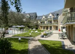 une pelouse avec des tables et des chaises devant un bâtiment