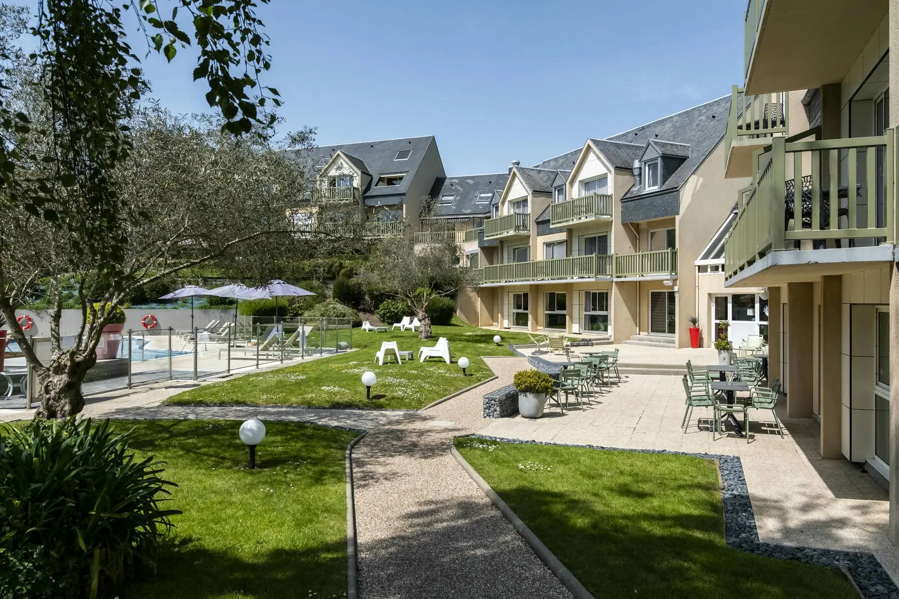une pelouse avec des tables et des chaises devant un bâtiment