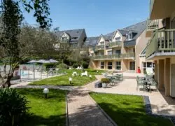 une pelouse avec des tables et des chaises devant un bâtiment