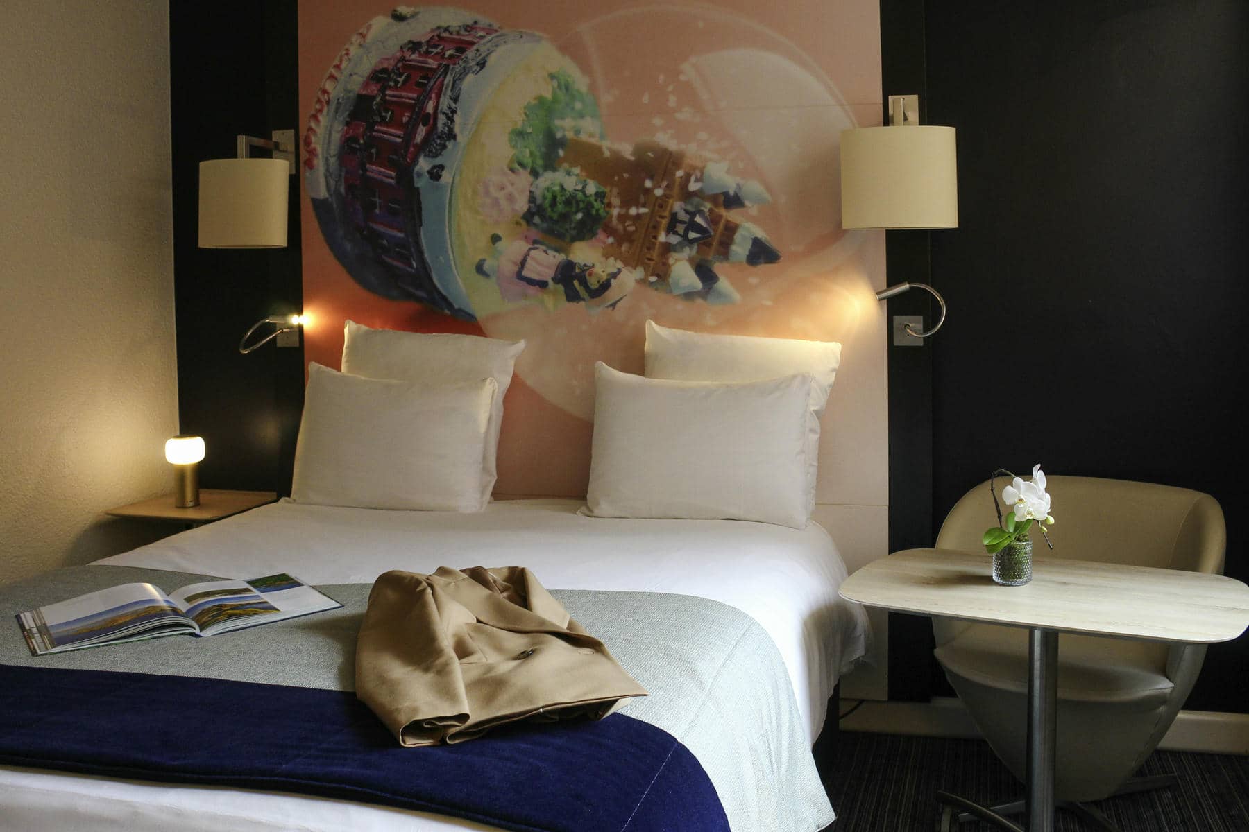 a hotel room with a painting on the wall behind the bed