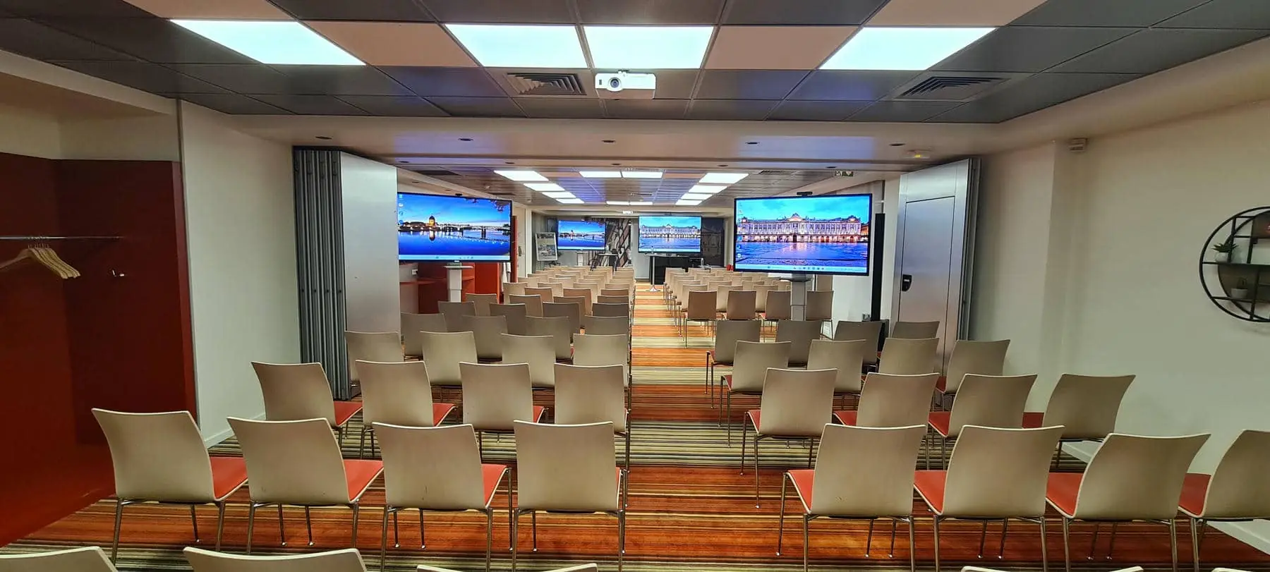 a conference room with rows of chairs and two large screens