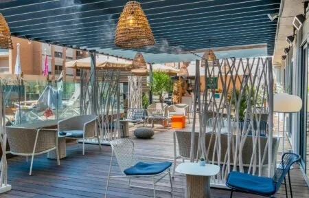 a patio with wicker chairs and tables under a canopy