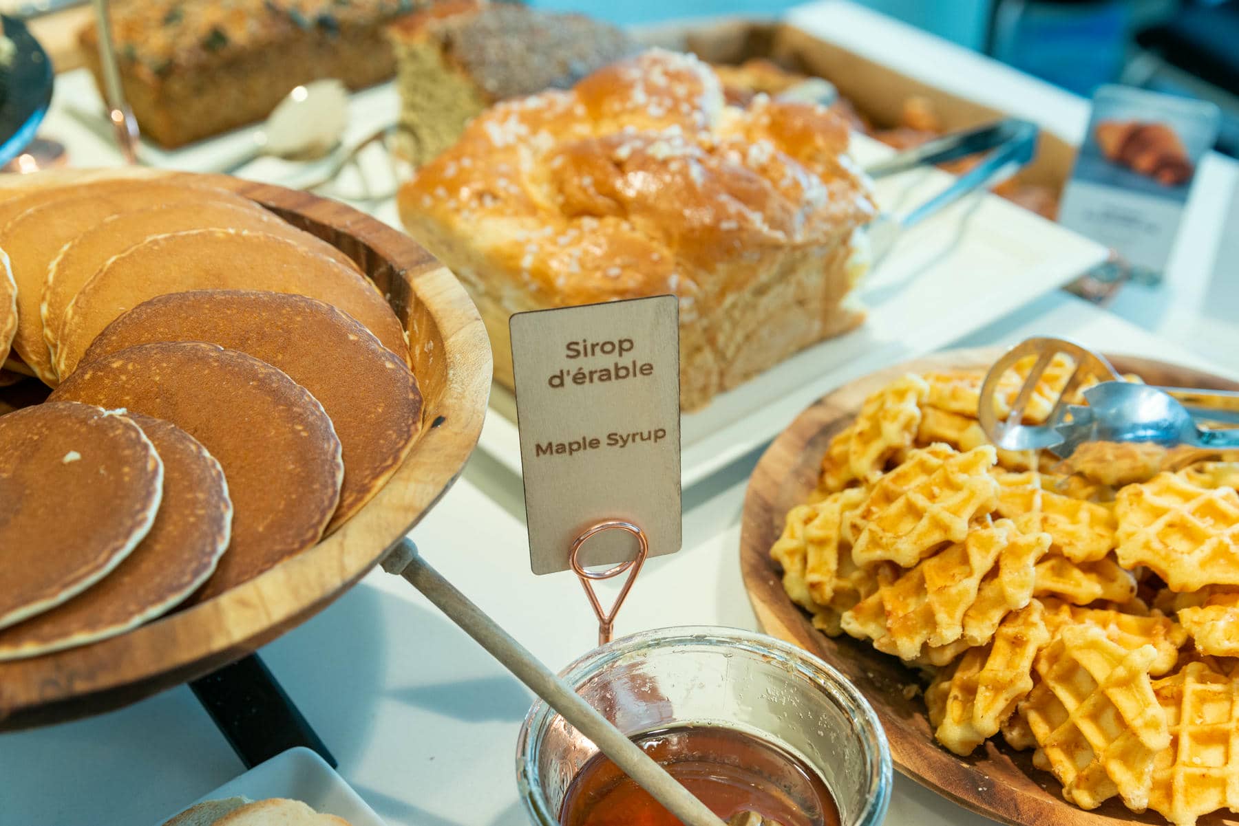 a jar of maple syrup sits next to a bowl of pancakes
