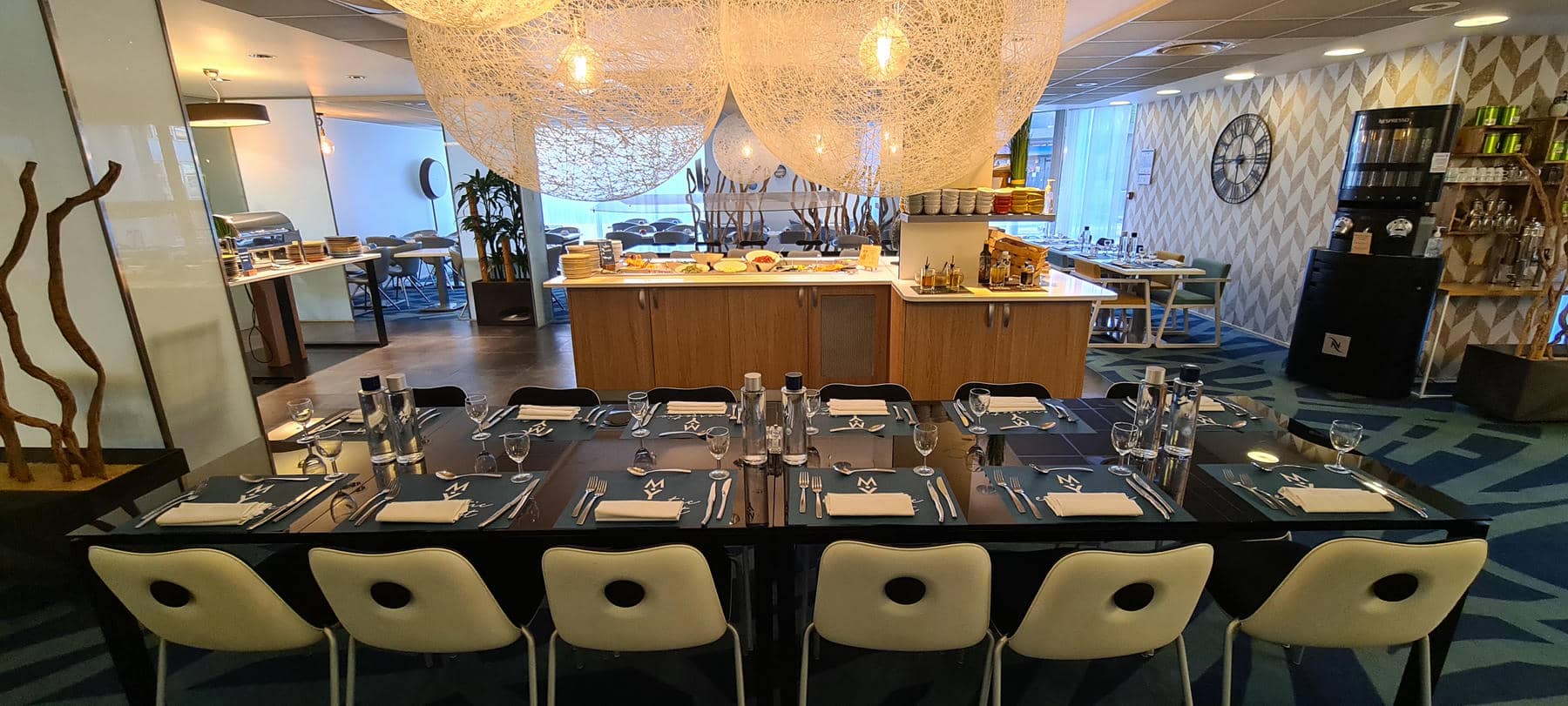 a long table with white chairs and silverware on it