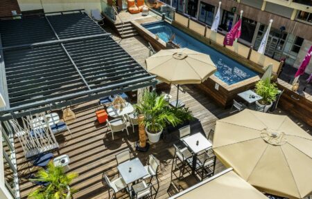 an aerial view of a deck with tables and umbrellas and a pool