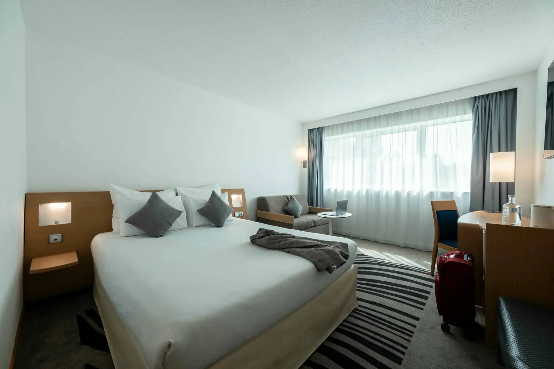 une chambre d'hôtel avec un grand lit et une valise rouge