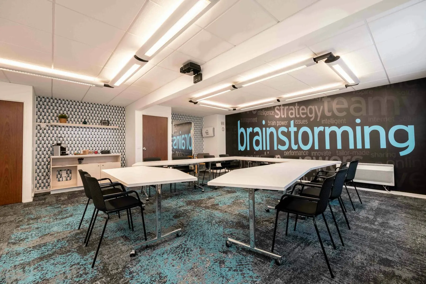 une salle avec des tables et des chaises et un mur sur lequel est écrit "brainstorming"