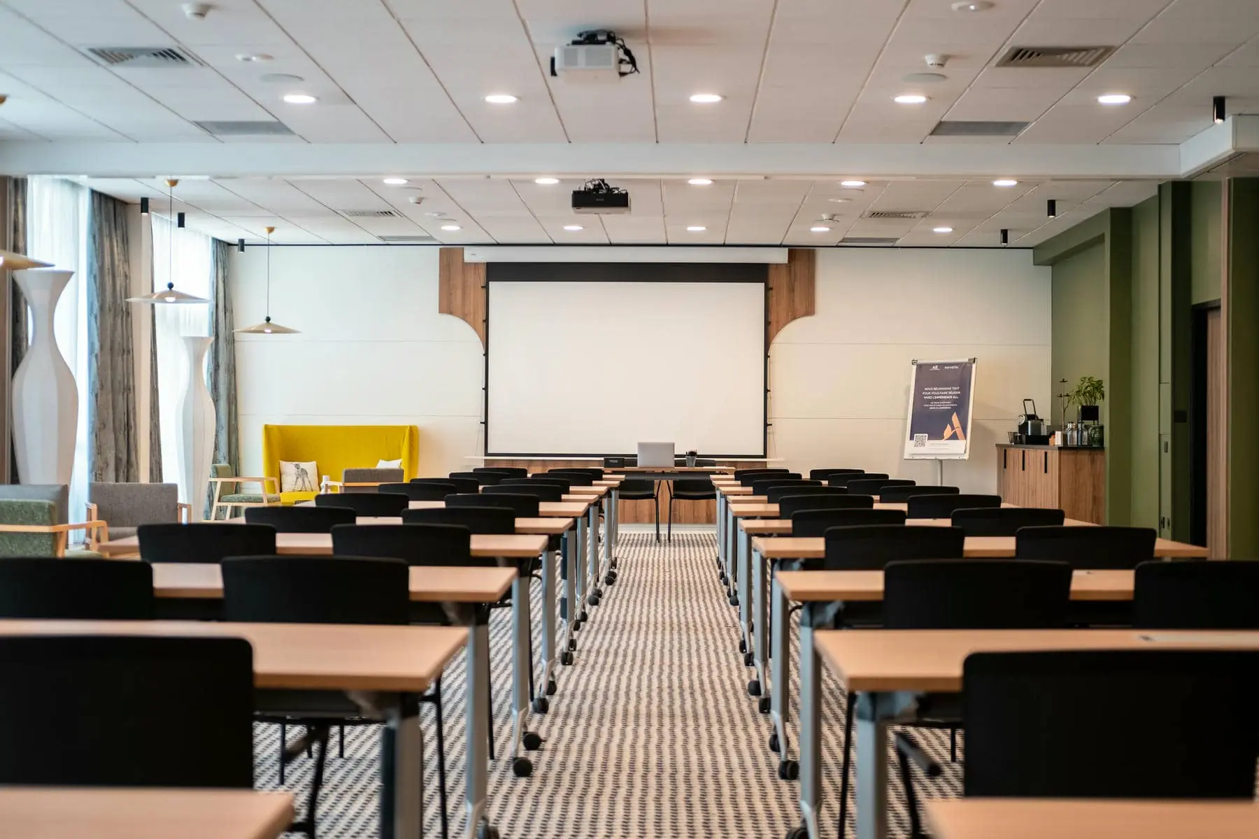 une salle de conférence vide avec des tables et des chaises et un écran de projection