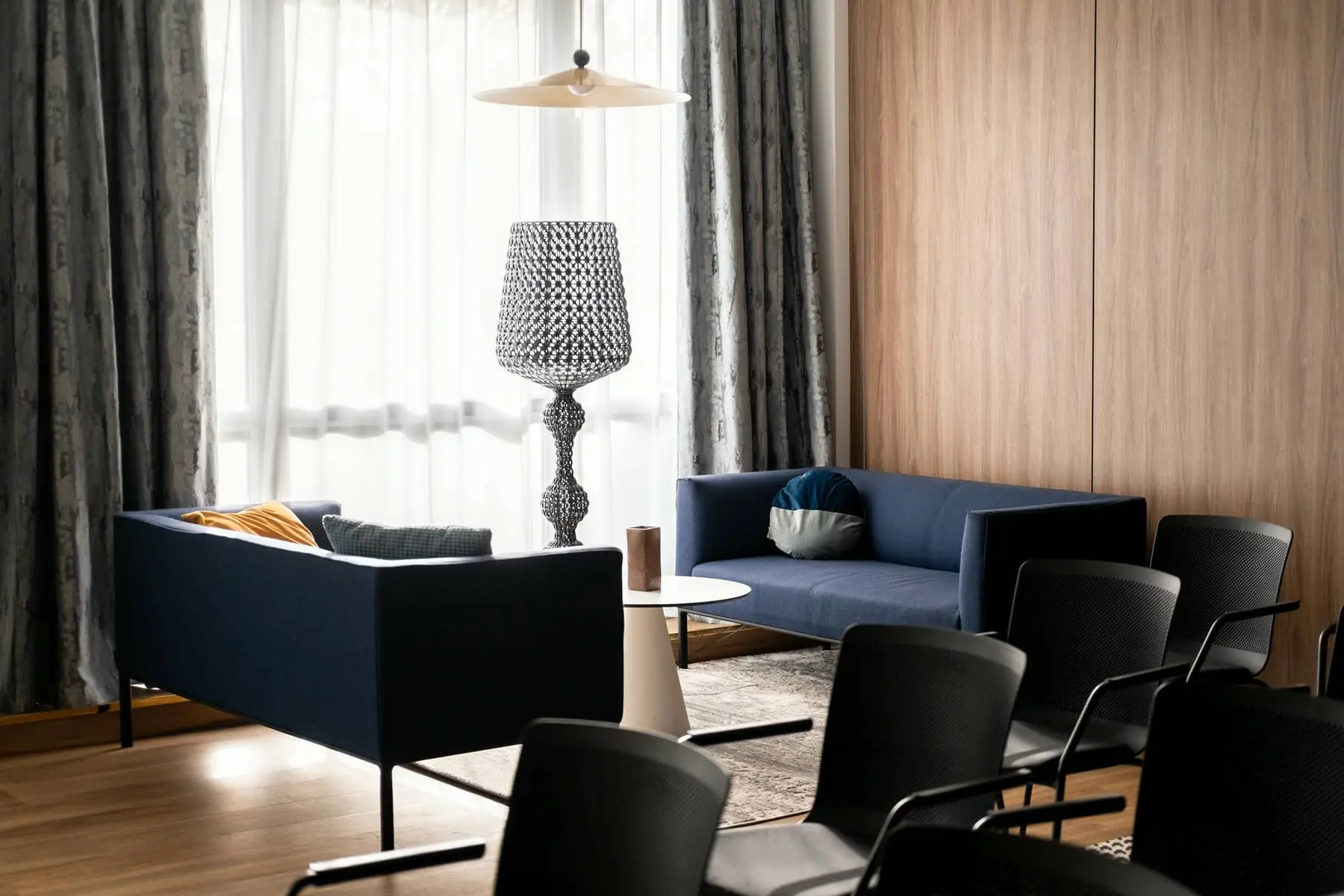 un salon avec un canapé bleu et des chaises noires