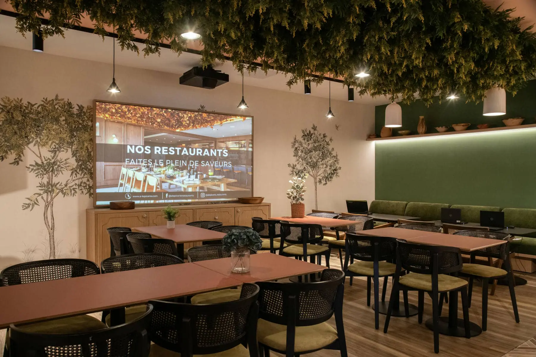 un restaurant avec des tables et des chaises et un grand écran sur lequel est écrit "nos restaurants"