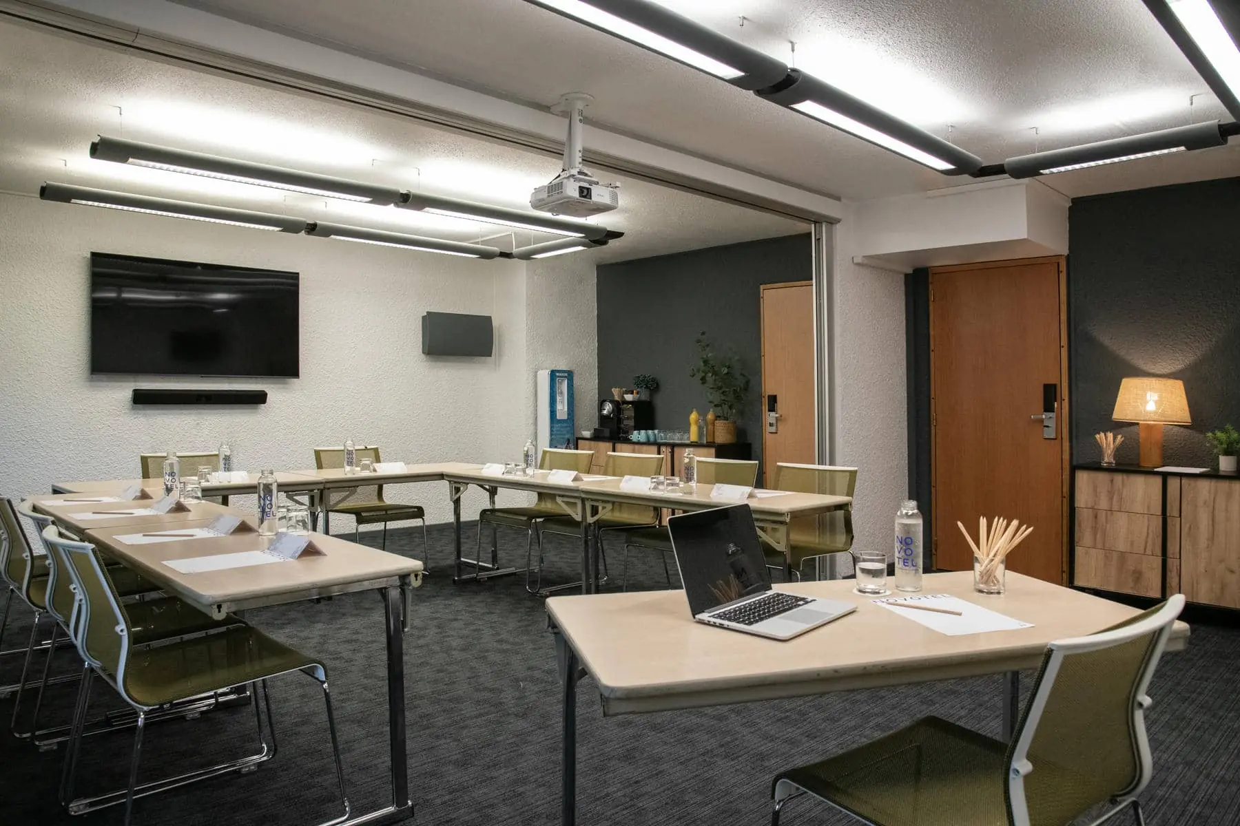une salle de conférence avec tables et chaises et un projecteur