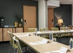 a conference room set up with tables and chairs and bottles of novotel water