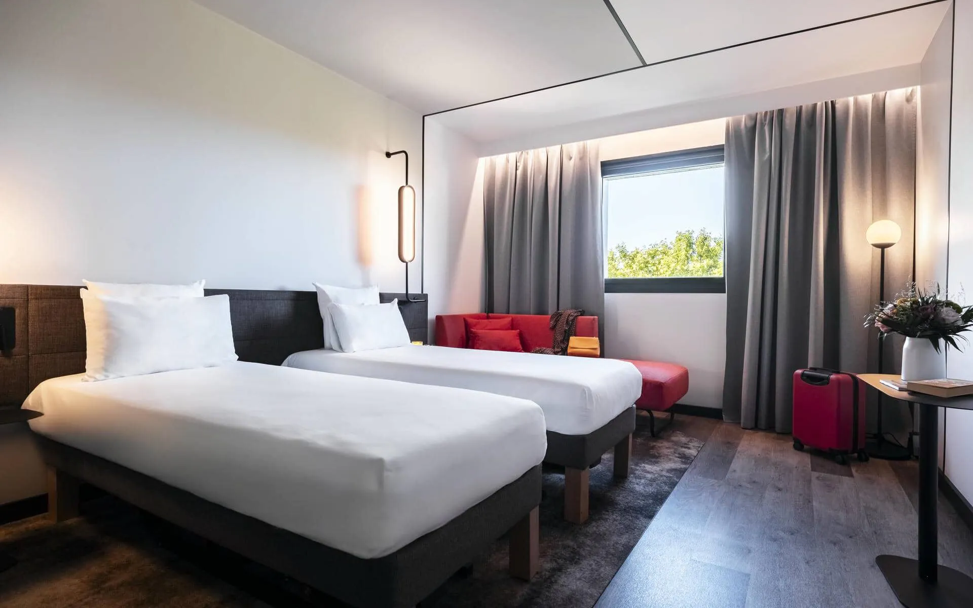 une chambre d'hôtel avec deux lits et un canapé rouge